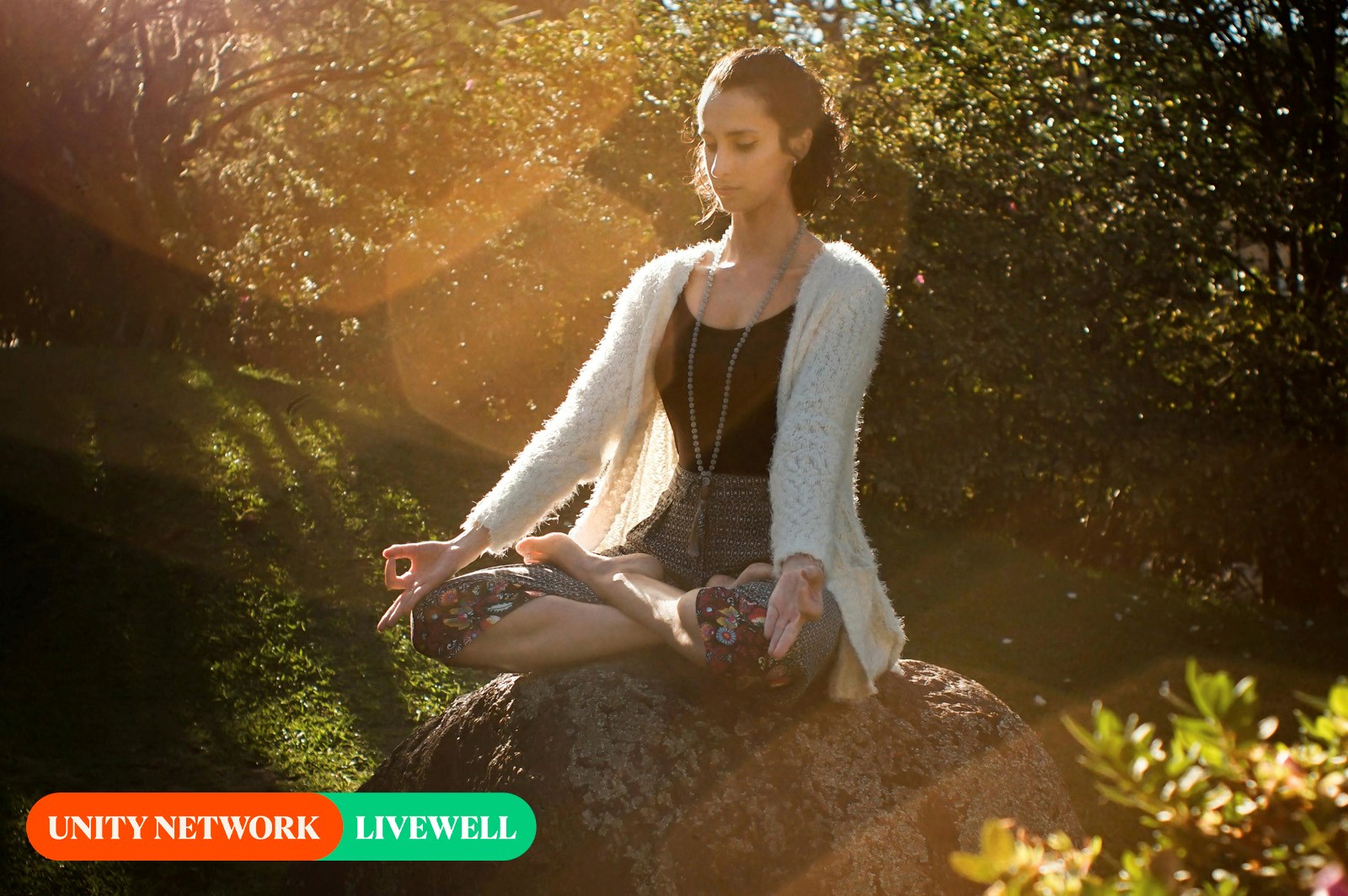 young woman meditating on a big rock in a forest