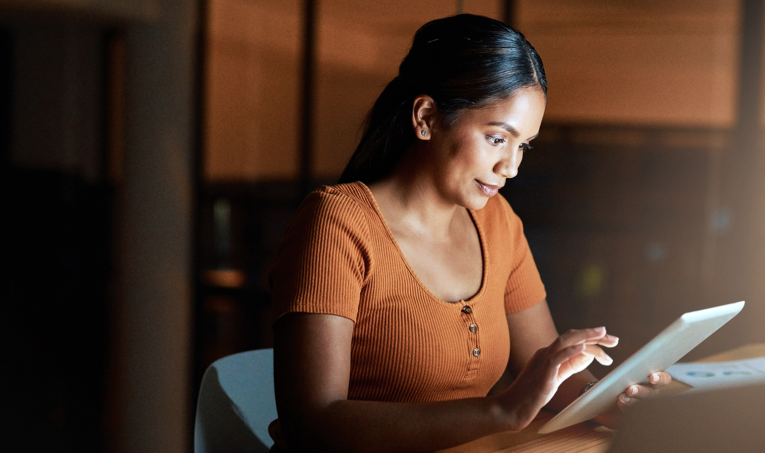 woman in orange t-shirt browsing on her tablet