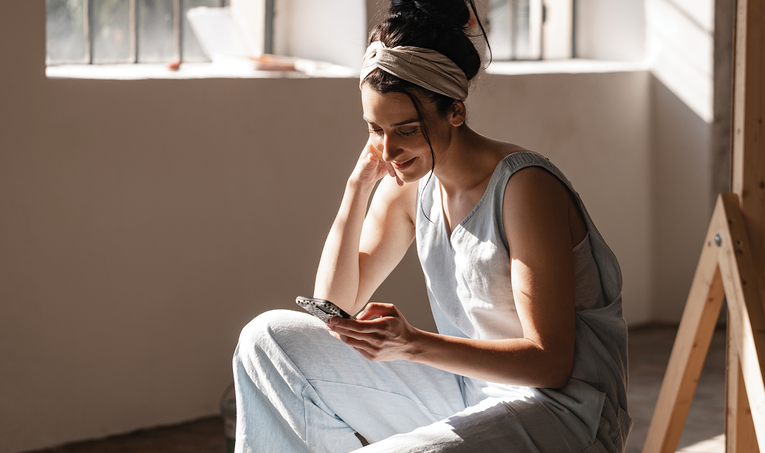 Woman sitting in an empty room browsing her phone