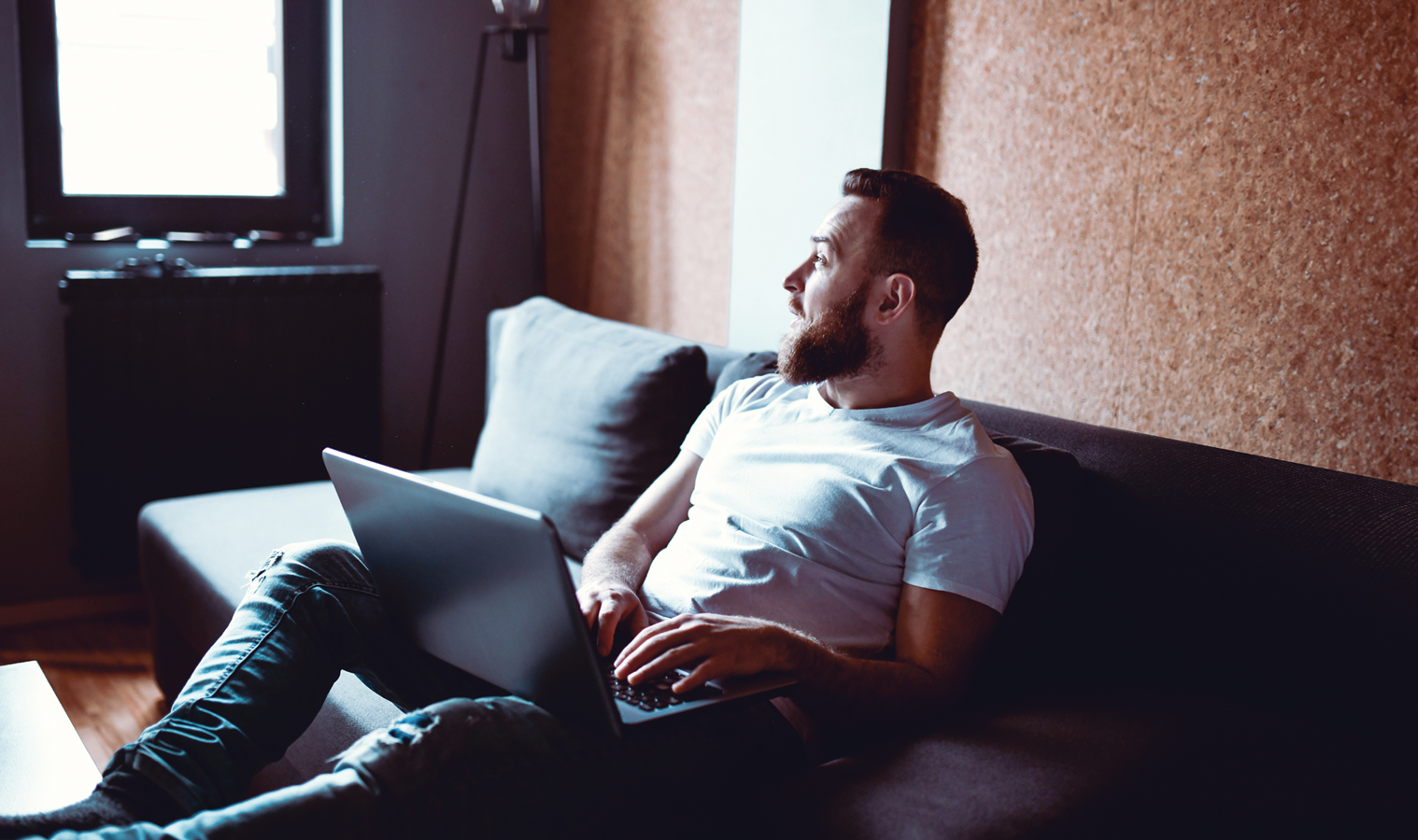 A young man sitting on the sofa with his laptop 