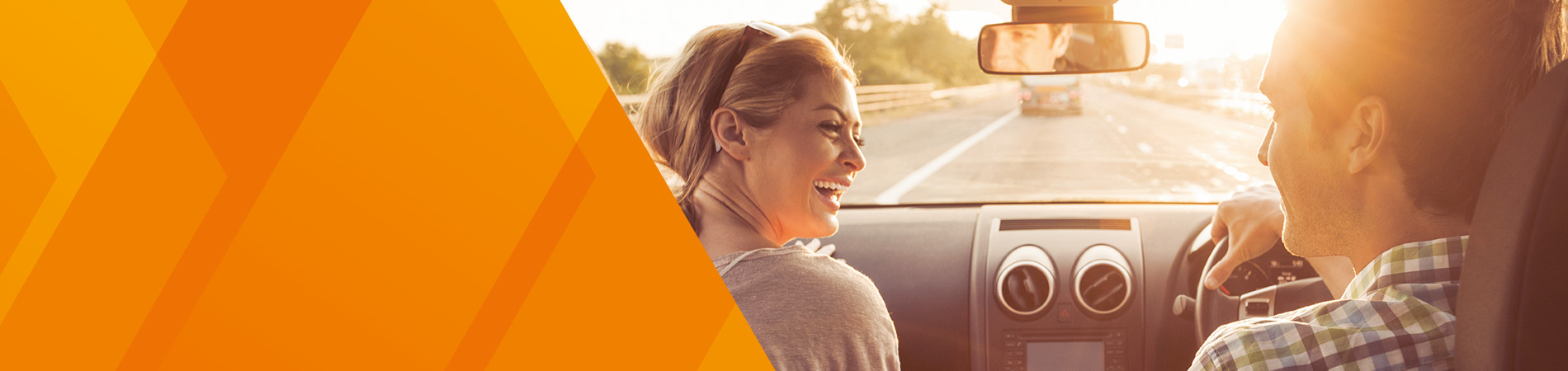 A woman laughing in the passenger seat of a car while the male driver is driving on the motorway