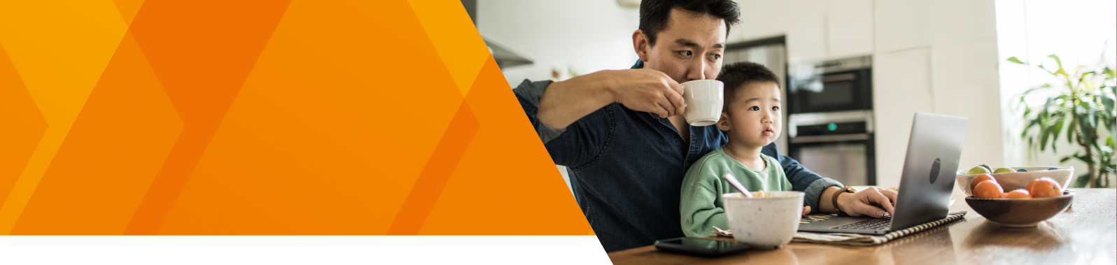 A man with his young son watching something on a laptop while drinking a tea